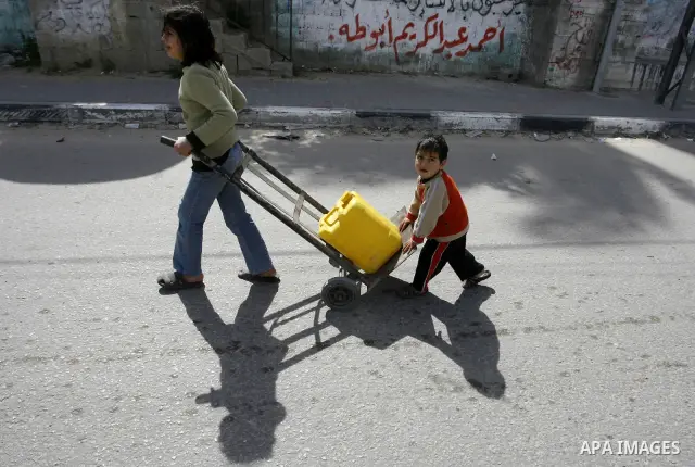 Palestinian children filling plastic bottles and jerry cans with drinking water from a public tap at the United Nations Relief and Works Agency (UNRWA) headquarters in the southern Gaza Strip refugee camp of Rafah on Mar...
