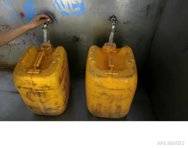 Palestinian children filling plastic bottles and jerry cans with drinking water from a public tap at the United Nations Relief and Works Agency (UNRWA) headquarters in the southern Gaza Strip refugee camp of Rafah on Mar...