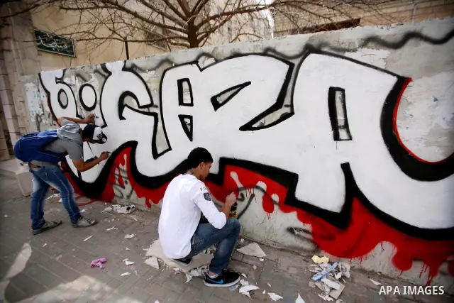 Palestinian students paint graffiti depicting word "Gaza" to show their support for the Gaza Strip and against Israeli air strikes, in the West Bank city of Hebron, on March 15, 2012. Photo by Mamoun Wazwaz.