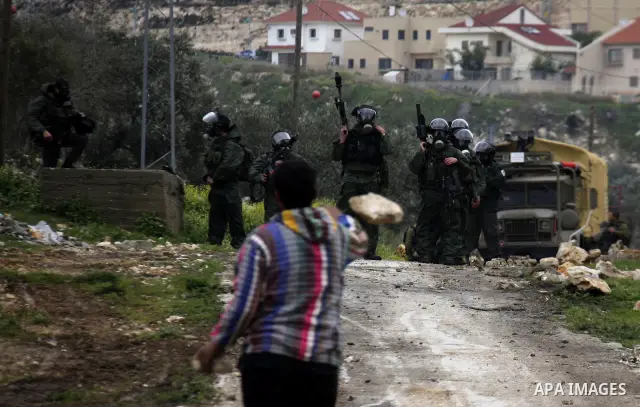Palestinian youths hurl stones at Israeli security forces ,during a protest in the village of Kufr Qaddum near the Israeli settlement of Kdumim, in the northern West Bank, Friday,March 16, 2012. Photo by Wagdi Eshtayah