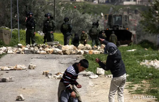Palestinian youths hurl stones at Israeli security forces ,during a protest in the village of Kufr Qaddum near the Israeli settlement of Kdumim, in the northern West Bank, Friday,March 16, 2012. Photo by Wagdi Eshtayah