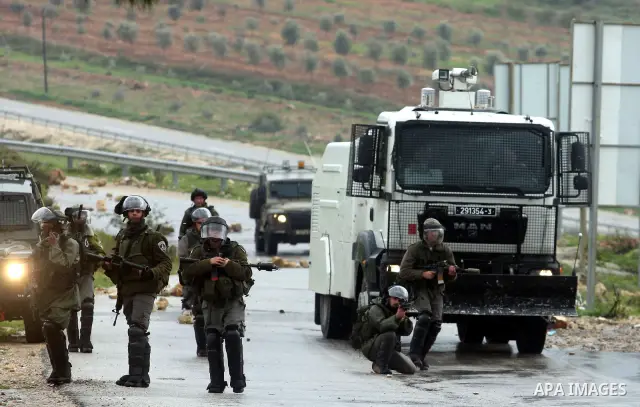 Israeli soldiers march during clashes with Palestinian and foreign activists in the West Bank village of Nabi Saleh, near Ramallah, on March 16, 2012 following a protest against Palestinian land confiscation to build the...
