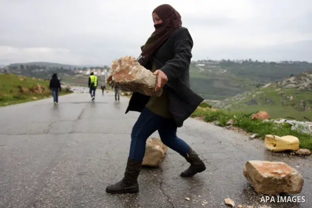A Palestinian protester hurls a stone at Israeli soldiers during a protest in the West Bank village of Nabi Saleh, near Ramallah, on March 16, 2012 against the confiscation of Palestinian land to build the Jewish settlem...