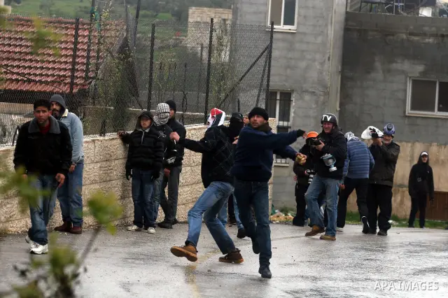 A Palestinian protester hurls a stone at Israeli soldiers during a protest in the West Bank village of Nabi Saleh, near Ramallah, on March 16, 2012 against the confiscation of Palestinian land to build the Jewish settlem...