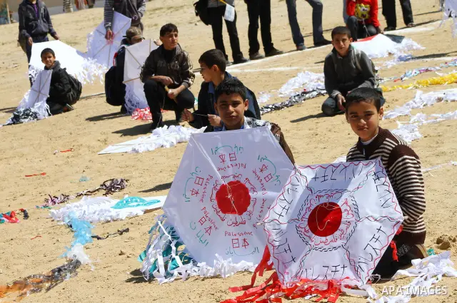 Palestinian children fly kites to show their solidarity with the Japanese people near a Japanese-funded housing project in Khan Younis in the southern Gaza Strip March 18, 2012. The event was organized by the United Nati...