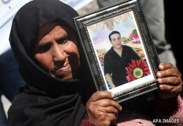 A Palestinian woman hold an image of her son, as she and other protest calling for the release of Palestinian prisoners being held in Israeli jails inside the grounds of the Red Cross headquarters in Gaza City on March 1...