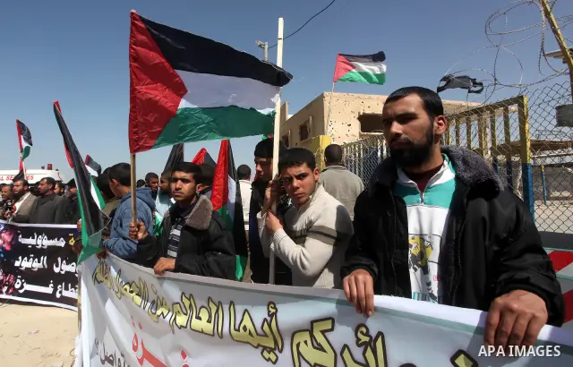 Palestinian demonstrators wave national flags during a protest in the Rafah border crossing with Egypt on March 19, 2012, demanding Egypt provide the Gaza Strip with electricity and fuel. The Palestinian energy authority...