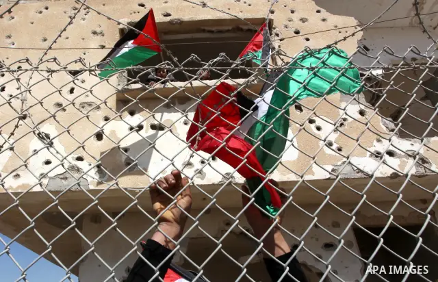 Palestinian demonstrators wave national flags during a protest in the Rafah border crossing with Egypt on March 19, 2012, demanding Egypt provide the Gaza Strip with electricity and fuel. The Palestinian energy authority...