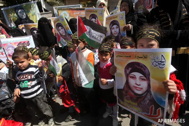 Palestinian children hold portraits of jailed compatriot Hana Shalabi, a female Palestinian prisoner jailed in Israel who has been on hunger strike for 37 days, outside the Red Cross building in Gaza City on Mar. 22, 201...