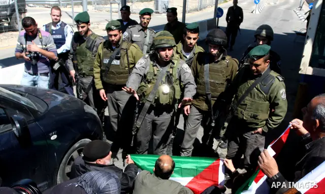 Israeli soldiers stand guard in front of Palestinian protesters demonstrating against the relocation of an Israeli road gate in the village of Beit Iksa in the occupied West Bank between Ramallah and Jerusalem on March 2...