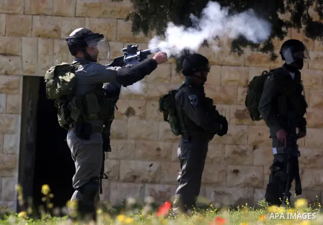 An Israeli soldier fires tear gas during clashes with Palestinian and foreign protestors in the occupied West Bank village of Nabi Saleh, near Ramallah, on March 23, 2012, following a protest against Palestinian land con...