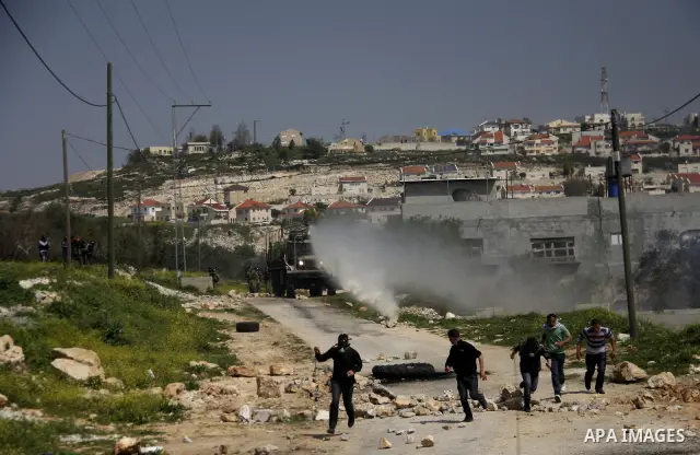 Palestinian protesters run away from a Israeli military vehicle spraying foul smelling water during clashes at a demonstration against the closure of a road for Palestinians in the West Bank village of Kfar Kadum, near N...