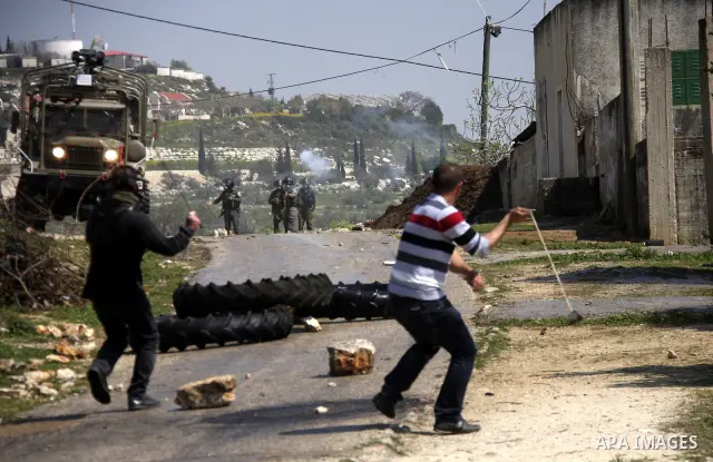 A Palestinian protester throws stones towards Israeli soldiers on March 23, 2012, during a protest against the closure of a road during the second Intifada (began late September 2000) by Jewish settlers from the nearby s...