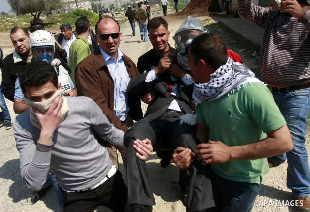 Palestinians carry an injured man during a protest in the village of Kufr Qaddum near the Israeli settlement of Kdumim, in the northern West Bank, Friday, March 23, 2012. Photo by Wagdi Eshtayah