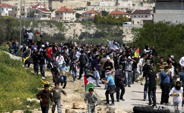 Palestinian protesters run away from a Israeli military vehicle spraying foul smelling water during clashes at a demonstration against the closure of a road for Palestinians in the West Bank village of Kfar Kadum, near N...