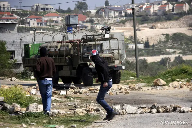 A Palestinian protester throws stones towards Israeli soldiers on March 23, 2012, during a protest against the closure of a road during the second Intifada (began late September 2000) by Jewish settlers from the nearby s...