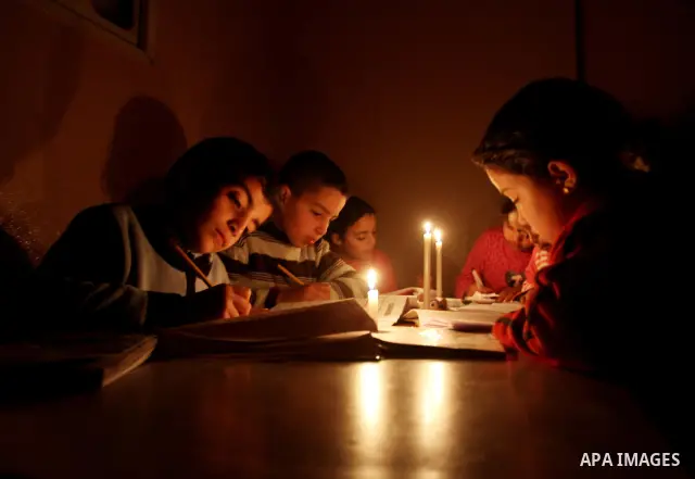 Palestinian children use a candle light during a power cut in Jabaliya refugee camp in the northern Gaza Strip 24 March 2012. The only remaining power plant in the Gaza Strip halted working because it run out of fuel, ca...