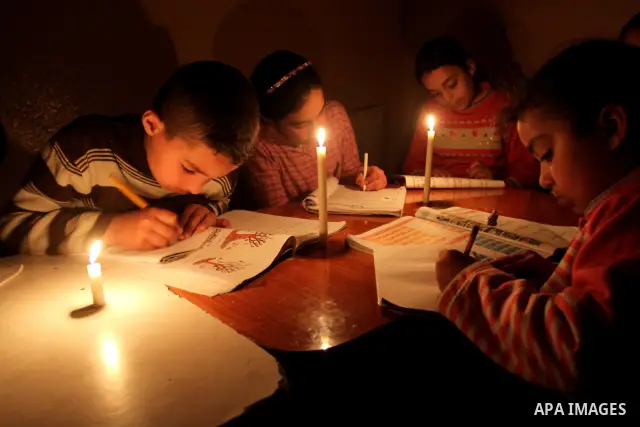 Palestinian children use a candle light during a power cut in Jabaliya refugee camp in the northern Gaza Strip 24 March 2012. The only remaining power plant in the Gaza Strip halted working because it run out of fuel, ca...
