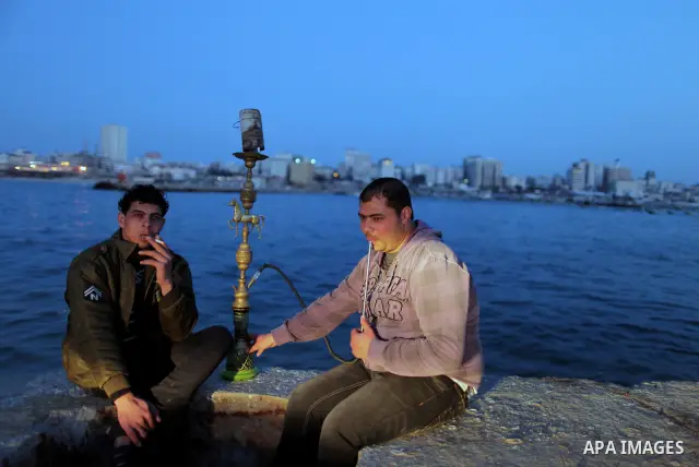 Palestinians enjoy their times during the sunset in Gaza fishing seaport, on March 23, 2012. Photo by Emad Nassar
