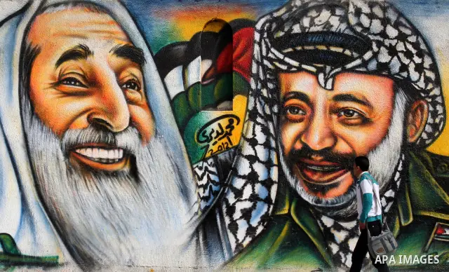 palestinians walk near of the mural of late Palestinian leader Yasser Arafat and late Hamas leader Sheikh Ahmed Yassin , in Gaza City on March 23, 2012. Photo by Emad Nassar