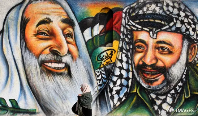 palestinians walk near of the mural of late Palestinian leader Yasser Arafat and late Hamas leader Sheikh Ahmed Yassin , in Gaza City on March 23, 2012. Photo by Emad Nassar