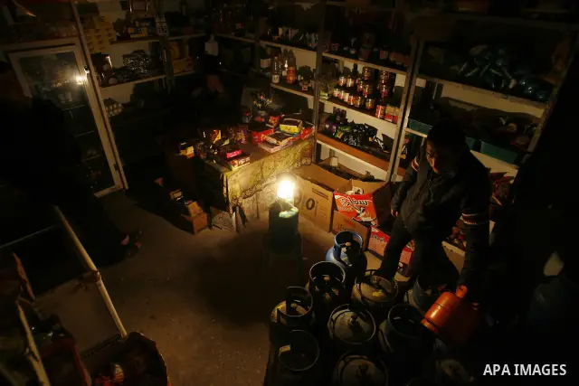 A Palestinian man sits in his shop during a blackout in Rafah on the southern Gaza Strip on, 26 March 2012. The only remaining power plant in the Gaza Strip halted working because it run out of fuel, causing a blackout,...