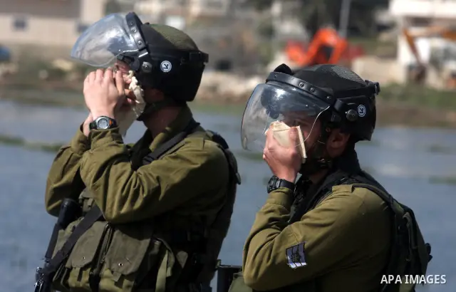 Israeli soldiers react after inhaling teargas during a protest outside the Ofer military prison, near the West Bank city of Ramallah Monday, March 26, 2012. Clashes between Palestinians and Israeli troops erupted during...