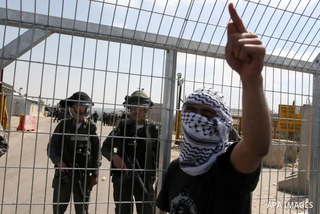 Masked Palestinian demonstrators call for the release of prisoners during a protest outside the Ofer military prison, near the West Bank city of Ramallah Monday, March 26, 2012. Clashes erupted during a demonstration cal...
