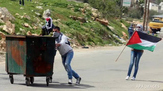 Palestinians clash with Israeli troops, not seen, during a protest outside the Ofer military prison, near the West Bank city of Ramallah Monday, March 26, 2012. Clashes erupted during a demonstration calling to release p...