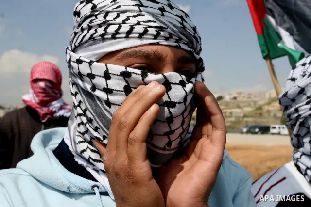 Masked Palestinian demonstrators call for the release of prisoners during a protest outside the Ofer military prison, near the West Bank city of Ramallah Monday, March 26, 2012. Clashes erupted during a demonstration cal...