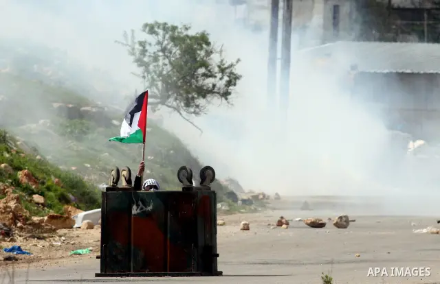 Palestinians clash with Israeli troops, not seen, during a protest outside the Ofer military prison, near the West Bank city of Ramallah Monday, March 26, 2012. Clashes erupted during a demonstration calling to release p...