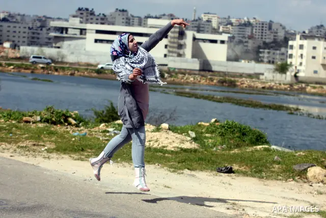 Palestinian demonstrators hurls stones at Israel troops, background, during clashes outside the Ofer military prison, near the West Bank city of Ramallah Monday, March. 26,2012. Clashes erupted during a demonstration cal...