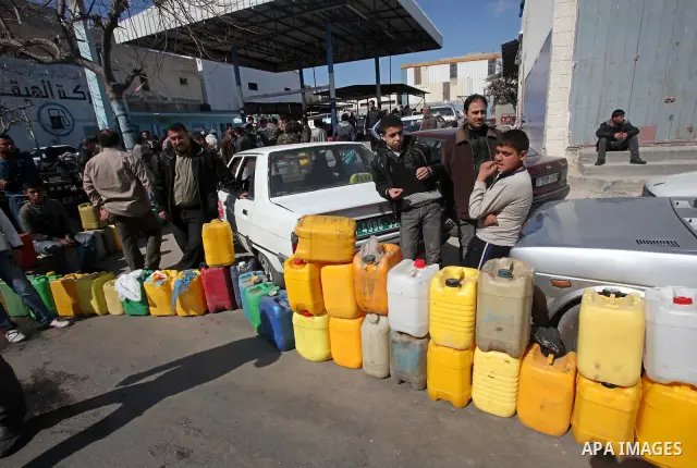 Palestinians wait to fill containers with fuel at a petrol station in Gaza City March 26, 2012. Palestinians in the Gaza Strip are suffering a crisis of dry petrol pumps and frequent blackouts triggered by a fuel supply...