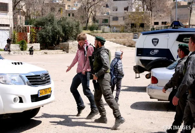 Israeli settlers walk past Israeli border policemen standing guard outside an occupied Palestinian house after dozens of Jewish settlers took over the property overnight, claiming they have legal ownership, in the occupi...