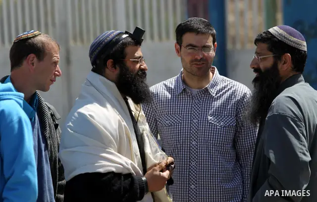 Israeli settlers stand at the entrance to an occupied Palestinian house after dozens of Jewish settlers took over the property overnight, claiming they have legal ownership, in the occupied West Bank city of Hebron on Ma...