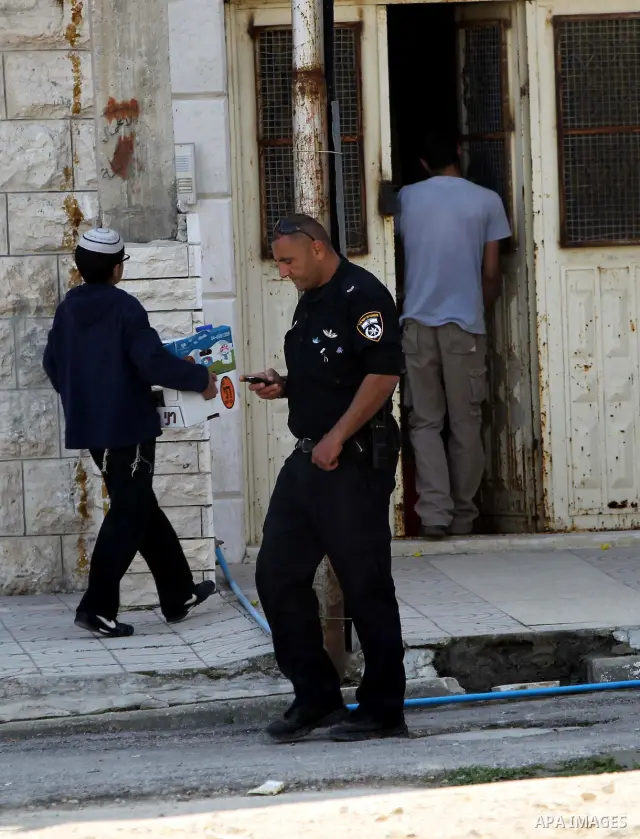 Israeli settlers stand at the entrance to an occupied Palestinian house after dozens of Jewish settlers took over the property overnight, claiming they have legal ownership, in the occupied West Bank city of Hebron on Ma...