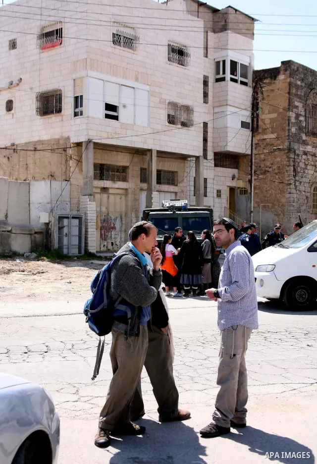 Israeli settlers stand at the entrance to an occupied Palestinian house after dozens of Jewish settlers took over the property overnight, claiming they have legal ownership, in the occupied West Bank city of Hebron on Ma...