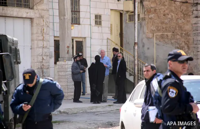 Israeli settlers walk past Israeli border policemen standing guard outside an occupied Palestinian house after dozens of Jewish settlers took over the property overnight, claiming they have legal ownership, in the occupi...