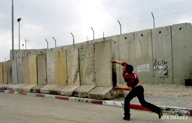 A Palestinian boy throw stones towards Israeli soldiers during clashes at the Qalandia checkpoint between the West Bank city of Ramallah and Jerusalem, on 29 March 2012. Photo by Mahfouz Abu Turk