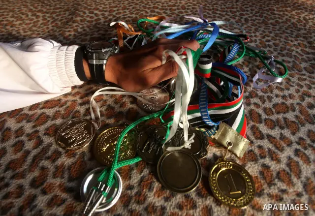 Gaza runner Bahaa al-Farra shows his medals at his house in Gaza City March 29, 2012. The 19-year-old trains for three hours a day in Gaza's Yarmouk soccer stadium, along the dusty streets and on the beach in well worn t...