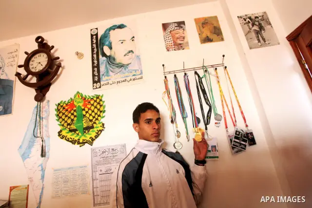 Gaza runner Bahaa al-Farra shows his medals at his house in Gaza City March 29, 2012. The 19-year-old trains for three hours a day in Gaza's Yarmouk soccer stadium, along the dusty streets and on the beach in well worn t...