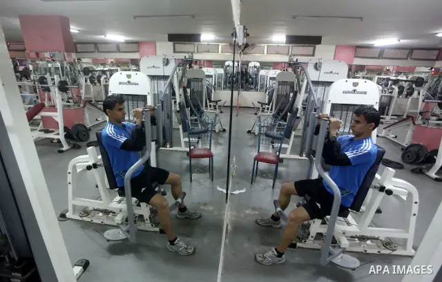 Gaza runner Bahaa al-Farra is reflected in a mirror as he trains at a gym in Gaza City March 29, 2012. The 19-year-old trains for three hours a day in Gaza's Yarmouk soccer stadium, along the dusty streets and on the bea...