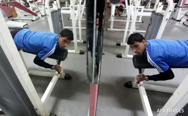Gaza runner Bahaa al-Farra is reflected in a mirror as he trains at a gym in Gaza City March 29, 2012. The 19-year-old trains for three hours a day in Gaza's Yarmouk soccer stadium, along the dusty streets and on the bea...