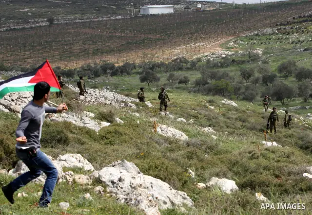 A Palestinian protester throws stones at Israeli soldiers during a demonstration to mark the anniversary of Land Day in the village Iraq Burin, near town of Nablus in the occupied Israeli West bank on March 30, 2012. Lan...