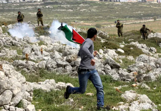A Palestinian protester runs to take cover from tear gas canisters fired by Israeli soldiers during a demonstration to mark the anniversary of Land Day in the village Iraq Burin, near town of Nablus in the occupied Israe...