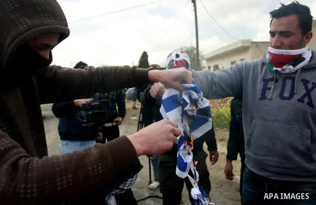 Palestinian protesters burn the Israeli flag during a demonstration to mark the anniversary of Land Day in the village Kafr Qaddum, close to the northern town of Nablus in the occupied Israeli West bank on March 30, 2012...