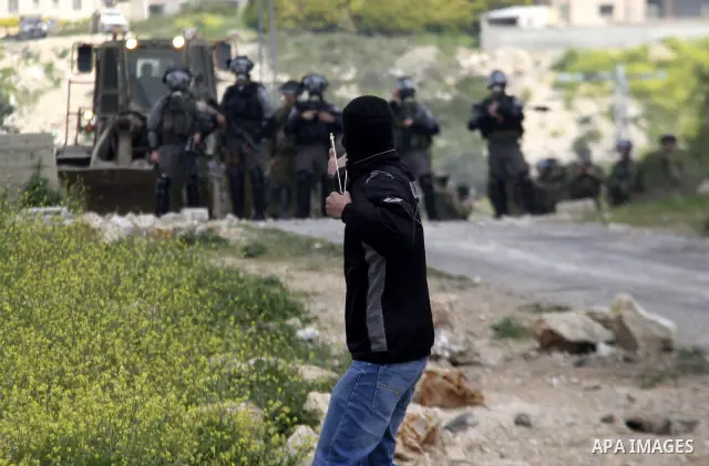 A Palestinian protester throws stones at Israeli soldiers during a demonstration to mark the anniversary of Land Day in the village Kafr Qaddum, close to the northern town of Nablus in the occupied Israeli West bank on M...