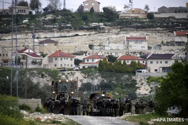 Israeli soldiers stand guards as Palestinian protesters throw stones during a demonstration to mark the anniversary of Land Day in the village Kafr Qaddum, close to the northern town of Nablus in the occupied Israeli Wes...