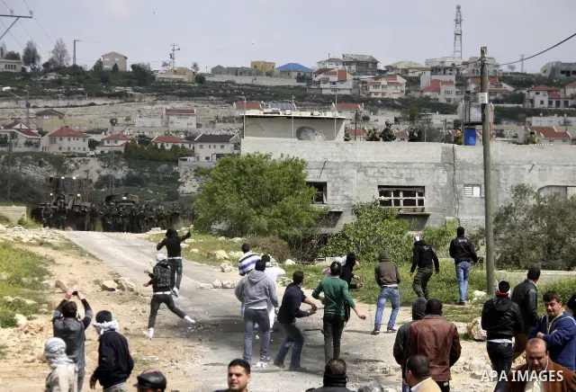 Palestinian protesters throw stones at Israeli soldiers during a demonstration to mark the anniversary of Land Day in the village Kafr Qaddum, close to the northern town of Nablus in the occupied Israeli West bank on Mar...