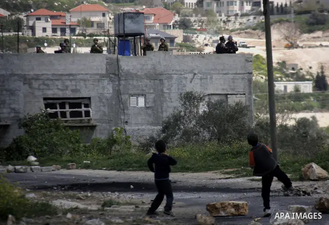 A Palestinian protester throws stones at Israeli soldiers during a demonstration to mark the anniversary of Land Day in the village Kafr Qaddum, close to the northern town of Nablus in the occupied Israeli West bank on M...